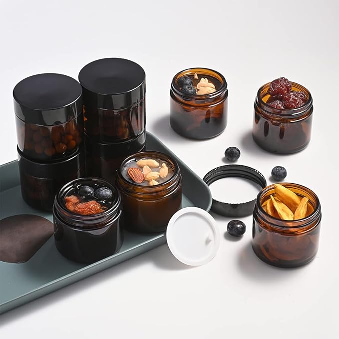 1 oz Amber Glass Jars with Lids, 105 pack Clear Small Jars with Black Lids, White Labels and Inner Liners, Empty Round Cosmetic Containers for Cream, Lotion (Amber 105 Pack)